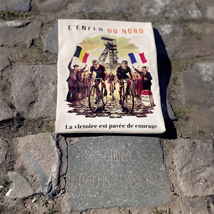 T-shirt en coton bio couleur ivoire marqué "L'Enfer du Nord"plié et posé sur des pavés du paris-Roubaix