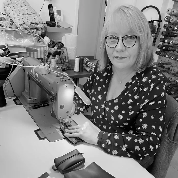 une technicienne œuvre à la confection d'un porte-monnaie dans un de nos ateliers partenaires